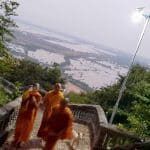 Buddhist monks in orange climbing a stairway